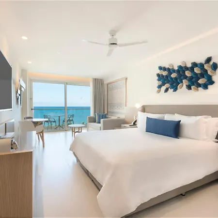 Royalton Splash Riviera Cancun, An Autograph Collection All-Inclusive Resort Puerto Morelos Room photo This is an image of a bright, modern, and luxurious hotel room with a beautiful view.

**Key Features:**

* **Bedroom Area:** The room features a large, comfortable-looking bed with white linens and a grey base. The headboard is upholstered in a neut